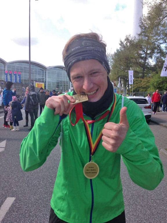 Kevin beißt auf seine Marathon Medaille