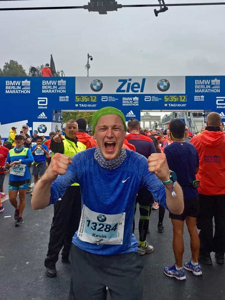 Ein begeisterter Läufer jubelt nach dem Ziel des BMW Berlin Marathon. Freude und Erfüllung strahlen von ihm aus!