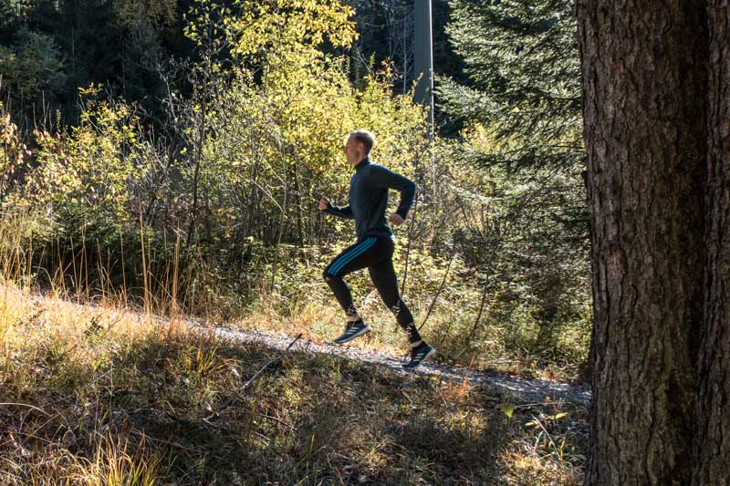 Ein Läufer joggt im Wald einen Berg hoch - Motivation für Läufer und Zitate beim Joggen.