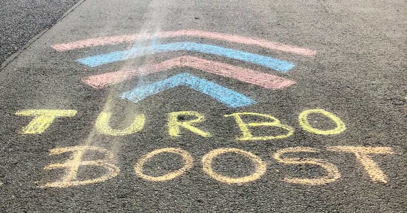 Jemand hat auf eine Straße den Begriff "Turbo Boost" gemalt - Die richtige Atemtechnik fürs Laufen finden.
