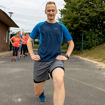 Lauftrainer Kevin macht eine Übung vor