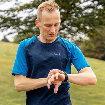 Lauftrainer Kevin schaut auf seine Laufuhr