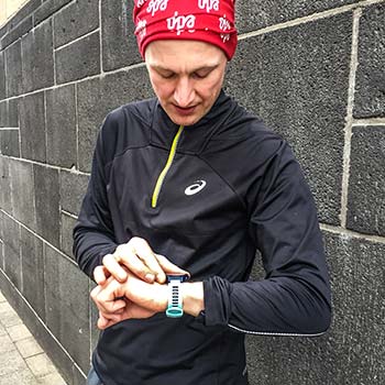 Lauftrainer Kevin schaut auf seine Laufuhr