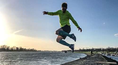 Ein Läufer am Fluss springt in die Luft