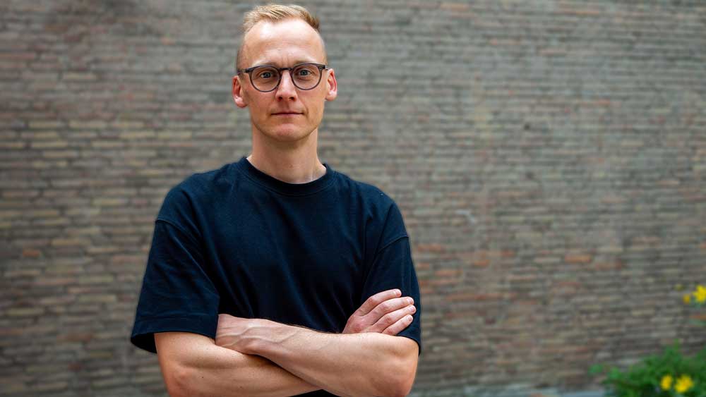 Lauftrainer Kevin von runnersflow steht mit verschränkten Armen vor einer Wand und guckt ernst