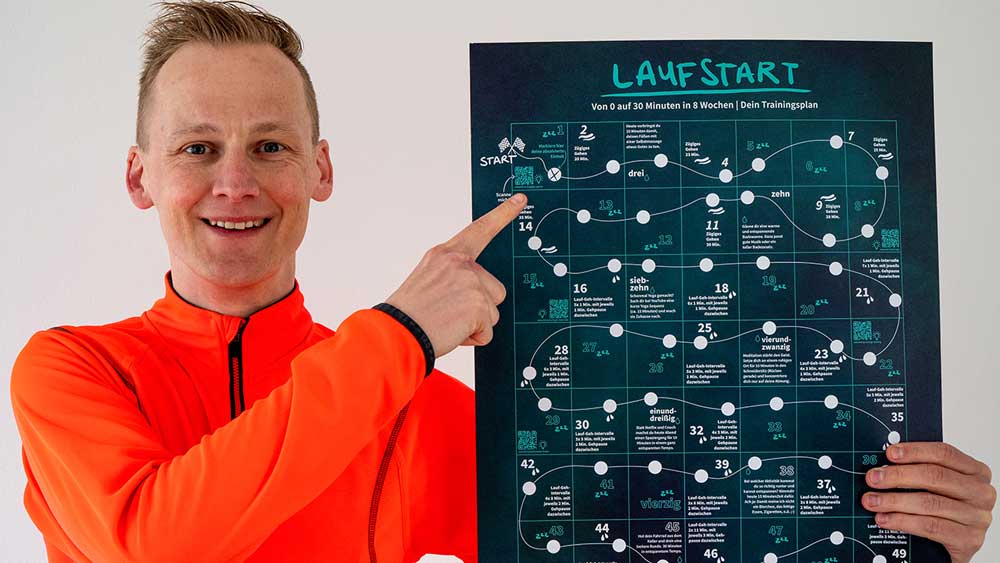 Lauftrainer Kevin von runnersflow hält einen Trainingsplan für Laufanfänger in der Hand
