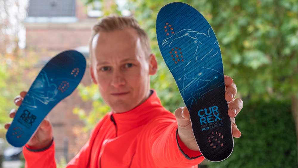 Lauftrainer Kevin hält Einlegesohlen zum Joggen in die Kamera