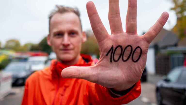 Ein motivierter Läufer zeigt stolz die Zahl 1000 auf seiner Hand, bereit für neue Joggen Tipps und Herausforderungen.