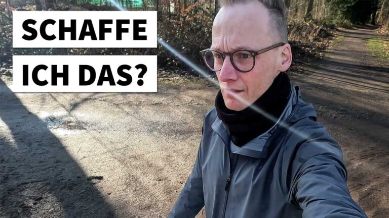 Ein Läufer auf einem Waldweg, nachdenklich und motiviert, bereit für das Marathon laufen. Die Sonne scheint durch die Bäume.