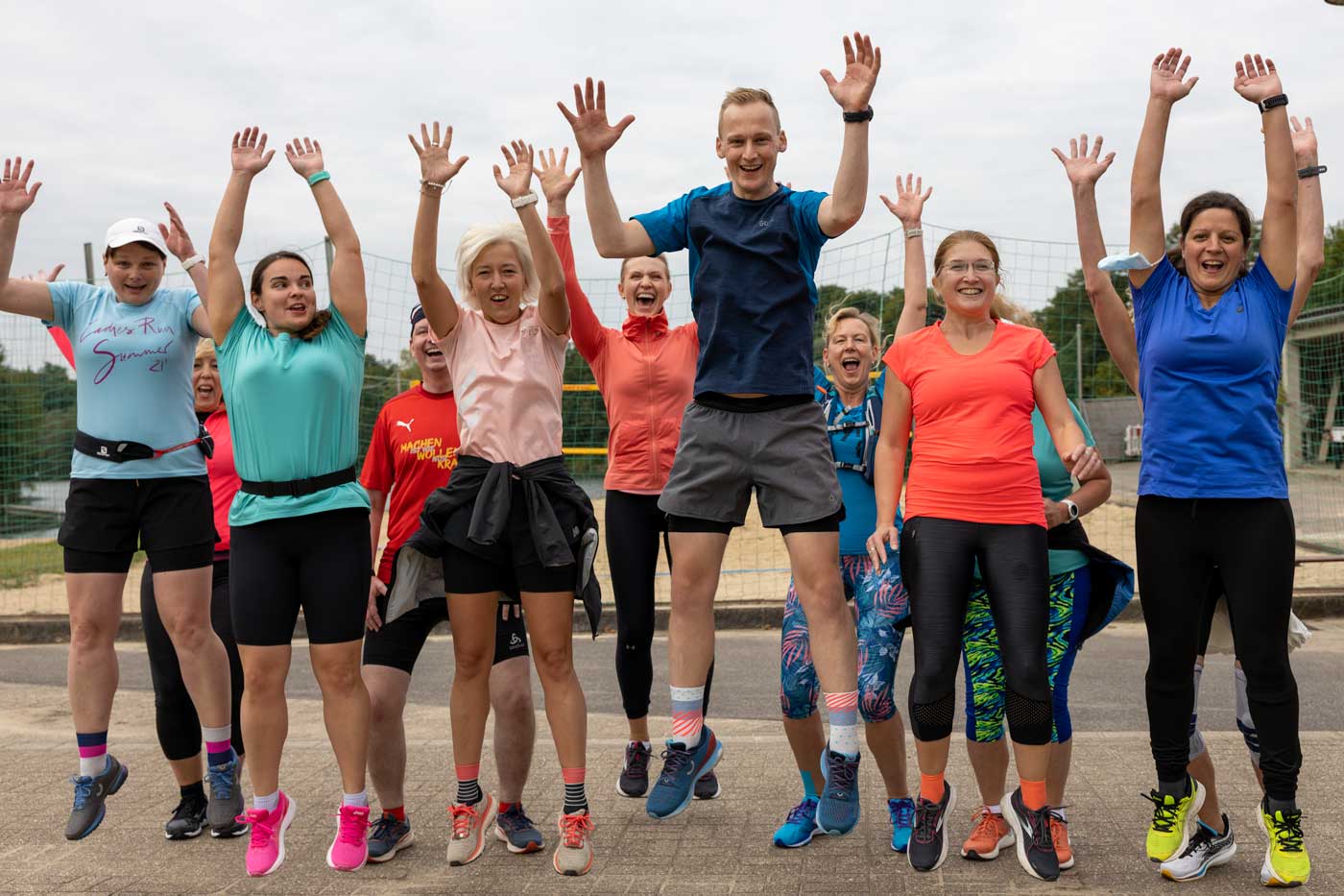 Eine fröhliche Gruppe von Läufern springt in die Luft, voller Energie und Freude beim Lauftraining in der Academy.