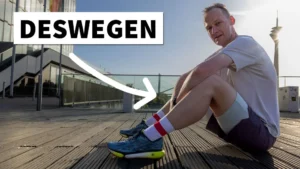 Ein Läufer sitzt entspannt auf einem Holzsteg und zeigt auf seine Laufschuhe, während er erklärt, warum viele Läufer nach 2 Jahren wieder aufhören.